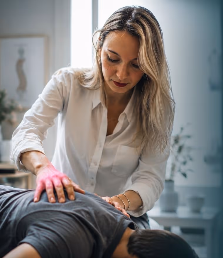 Sophie Baltaci, quiropráctica, realizando un ajuste a un paciente en su consulta de París 2e, con luz natural suave.