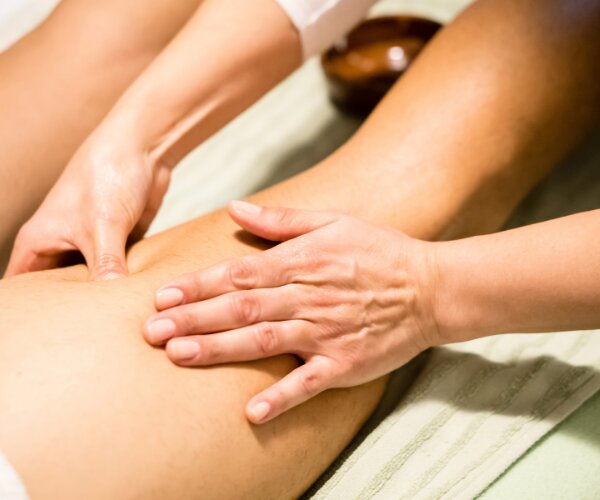 Massage manuel d'un muscle de la cuisse — illustration du travail sur un trigger point en cabinet